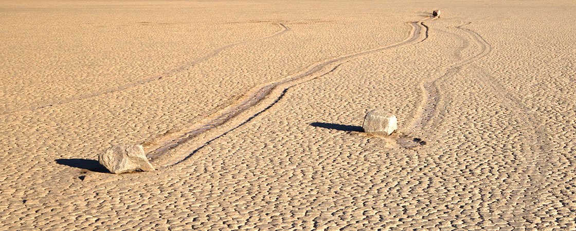 Two rocks in the middle of the desert that appears to have moved through the sand