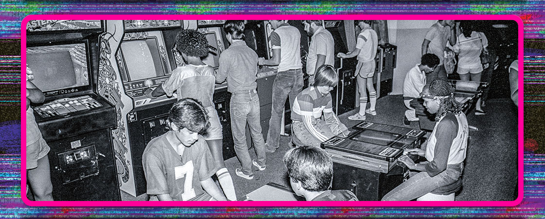 black and white photo of kids playing at an arcade