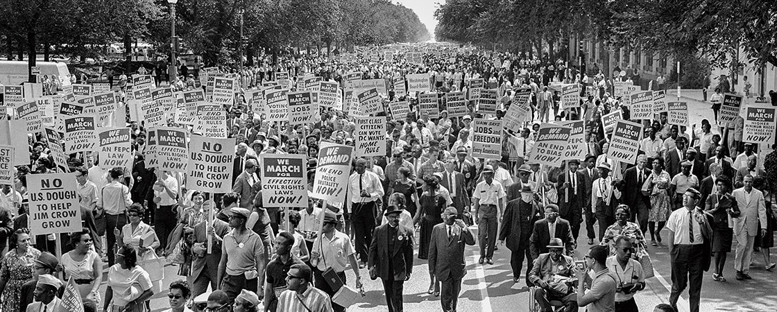 Black & white photo of people marching & protesting with signs